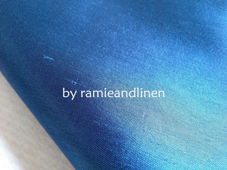 May include: Close-up of a deep blue fabric with a subtle sheen. The fabric is smooth and has a fine weave. The text "by ramieandlinen" is visible in the lower center of the image.