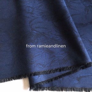 May include: Close-up of a dark blue fabric with a subtle embossed pattern. The fabric has a fringed edge and the text "from ramieandlinen" is visible in the lower center of the image.