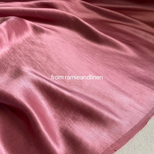 Pode incluir: Um close-up de um tecido rosa com um brilho lustroso. O tecido é drapeado, mostrando dobras e texturas. O texto "from ramieandlinen" é visível no canto inferior esquerdo.