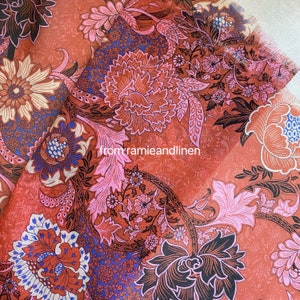 Puede incluir: Primer plano de una tela con estampado floral en tonos rojos, rosas y azules. El diseño presenta grandes flores, hojas y detalles intrincados. El texto "from ramieandlinen" es visible.