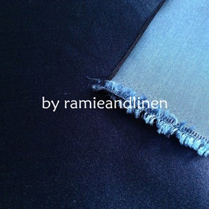 May include: Close-up of two different shades of blue denim fabric. The top fabric is a lighter shade of blue and has a frayed edge. The bottom fabric is a darker shade of blue. The text "by ramieandlinen" is visible in the image.