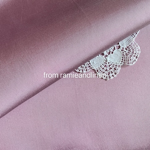 May include: A close-up of a mauve fabric with a white lace overlay. The lace has a delicate heart pattern. The text "from ramieandlinen" is visible in the lower left corner.