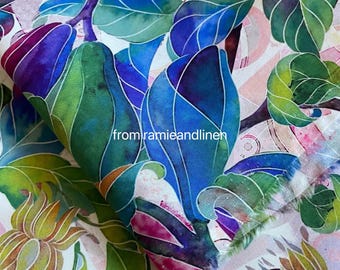 Op de afbeelding: Stof met een botanisch ontwerp met blauwe, groene en paarse bladeren en bloemknoppen. De stof heeft een witte achtergrond met roze en groene bloemaccenten. De tekst "from ramieandlinen" is zichtbaar.