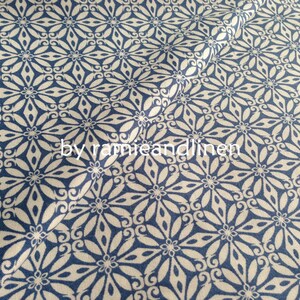 May include: White fabric with a blue floral pattern. The fabric has a repeating pattern of stylised flowers with a blue background. The text "by ramieandlinen" is visible in the centre of the image.