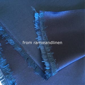 May include: Close-up of two pieces of dark blue fabric with a fringed edge. The fabric has a smooth, silky texture. The text "from ramieandlinen" is visible in the image.