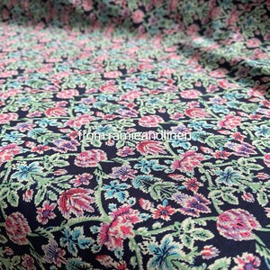 May include: A navy blue fabric with a floral print featuring pink, purple, and blue flowers. The fabric has a subtle texture and a repeating pattern.