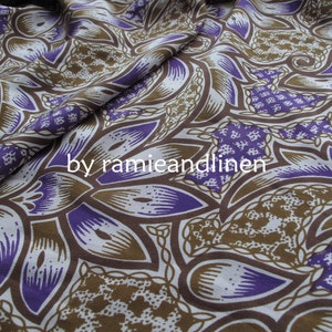 May include: Purple and brown patterned fabric with a repeating design of stylized leaves and flowers. The fabric is made of a blend of ramie and linen.