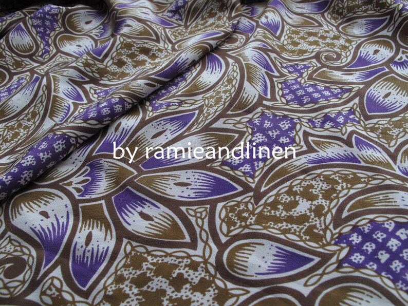 May include: Purple and brown patterned fabric with a repeating design of stylized leaves and flowers. The fabric is made of a blend of ramie and linen.