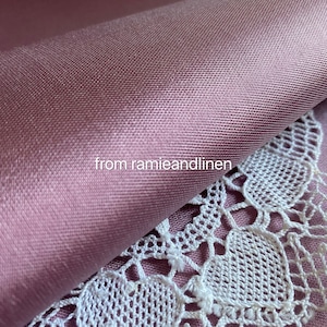 May include: Close-up of a soft, smooth, mauve fabric with a subtle sheen. The fabric is folded over a white lace doily. The text "from ramieandlinen" is visible in the image.