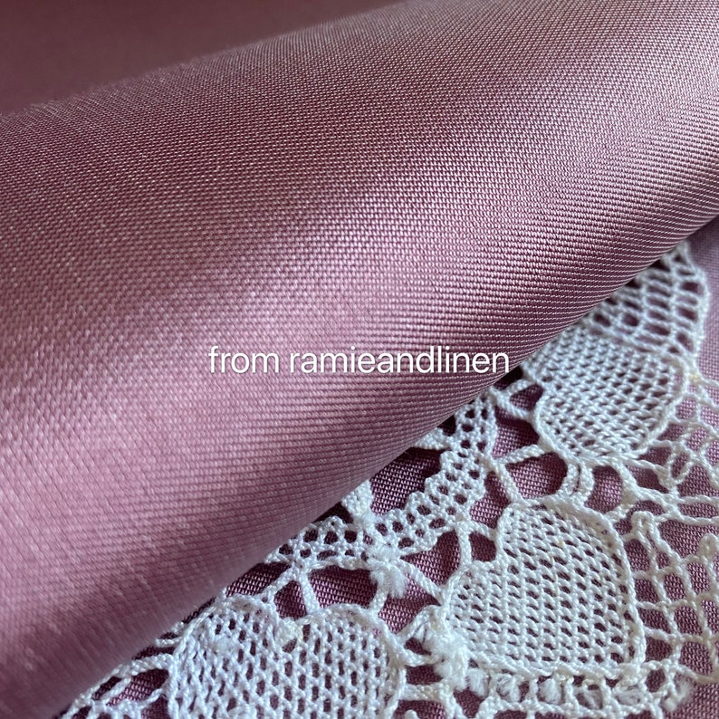 May include: Close-up of a soft, smooth, mauve fabric with a subtle sheen. The fabric is folded over a white lace doily. The text "from ramieandlinen" is visible in the image.
