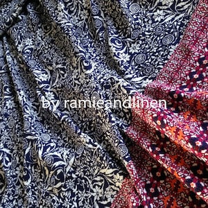 Pu&ograve; includere: Primo piano di due campioni di tessuto. Uno &egrave; un tessuto blu navy con un motivo floreale bianco. L'altro &egrave; un tessuto rosso, arancione e blu con un motivo geometrico. Il testo "by ramieandlinen" &egrave; visibile nell'immagine.
