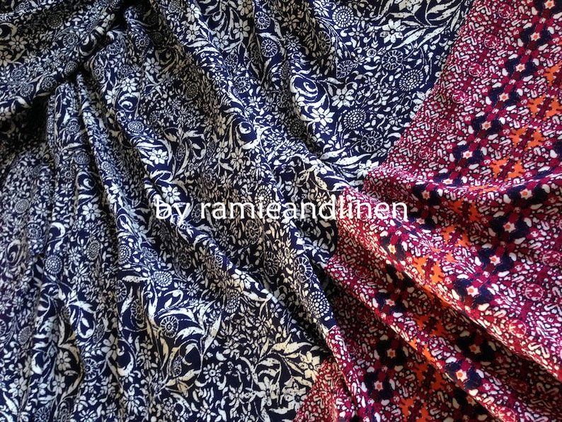 Pu&ograve; includere: Primo piano di due campioni di tessuto. Uno &egrave; un tessuto blu navy con un motivo floreale bianco. L'altro &egrave; un tessuto rosso, arancione e blu con un motivo geometrico. Il testo "by ramieandlinen" &egrave; visibile nell'immagine.