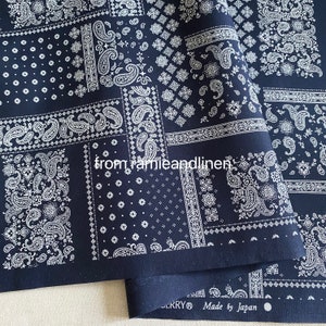 May include: A close-up of a dark blue fabric with a white paisley pattern. The fabric is folded in half and the text "Made by Japan" is visible on the bottom edge.