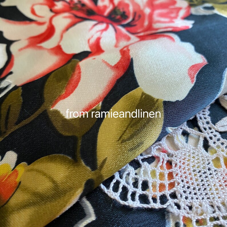 May include: Close-up of a black fabric with a white floral pattern. The fabric has a satin-like sheen and is layered over a white crocheted lace trim. The text "from ramieandlinen" is visible in the image.