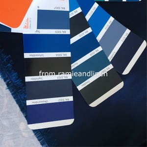 May include: A close-up of a color chart with various shades of blue, from dark blue to light blue. The chart is labeled with RAL color codes and names, such as "Ultramarinblau", "Saphirblau", and "Graublau".