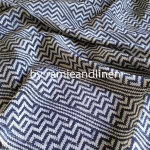 May include: Black and white chevron patterned fabric. The fabric has a textured weave and a subtle sheen.
