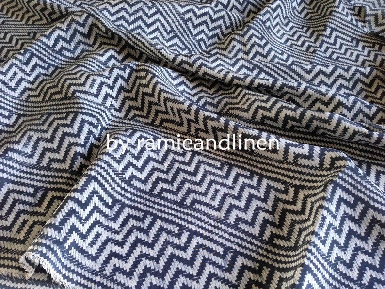 May include: Black and white chevron patterned fabric. The fabric has a textured weave and a subtle sheen.