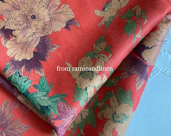 May include: Red linen fabric with a floral print featuring large, beige flowers and green leaves. The fabric is folded in half, and the text "from ramieandlinen" is visible in the center of the image.