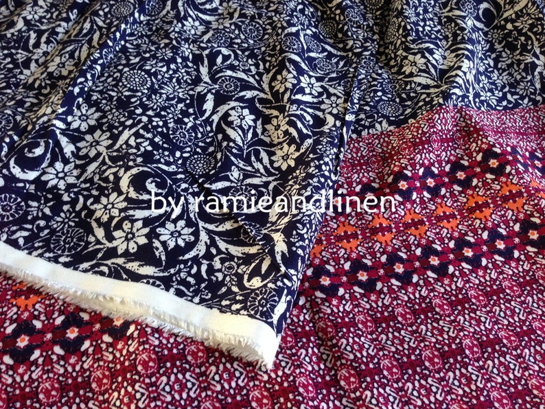Pu&ograve; includere: Due campioni di tessuto con motivi diversi. Il campione superiore &egrave; un tessuto blu navy con un motivo floreale bianco. Il campione inferiore &egrave; un tessuto rosso con un motivo geometrico bianco e arancione. Il testo "by ramie and linen" &egrave; visibile sul tessuto.