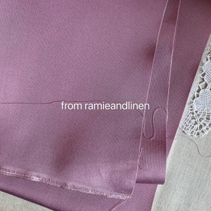 May include: Close-up of a folded piece of mauve fabric with a raw edge. The fabric is smooth and has a subtle sheen. The text "from ramieandlinen" is visible in the image.