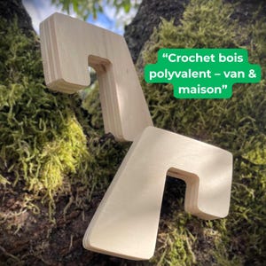 Puede incluir: Dos ganchos de madera de color claro con un diseño angular único se muestran sobre un fondo de corteza de árbol musgosa. Los ganchos están colocados en diferentes ángulos, mostrando su forma. El texto en la imagen dice "Crochet bois polyvalent - van & maison".