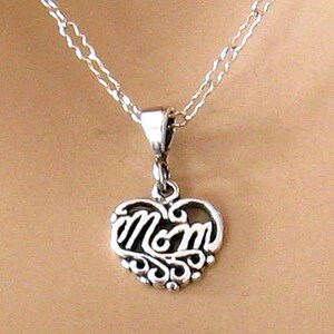 May include: A silver necklace with a heart-shaped pendant that says "Mom" in a cursive script.