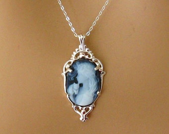 May include: A silver chain necklace with a cameo pendant. The cameo features a black and white profile of a woman in an ornate silver frame.