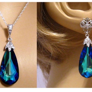 May include: A teardrop-shaped pendant necklace and matching earrings with a large blue crystal and silver accents.