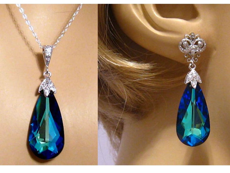 May include: A teardrop-shaped pendant necklace and matching earrings with a large blue crystal and silver accents.