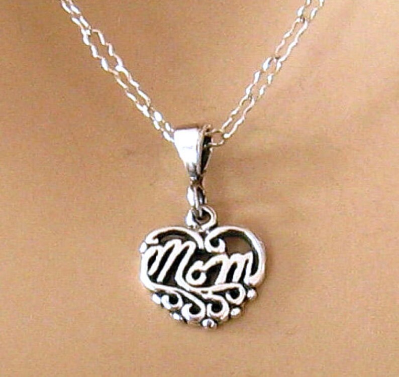 May include: A silver necklace with a heart-shaped pendant that says "Mom" in a cursive script.