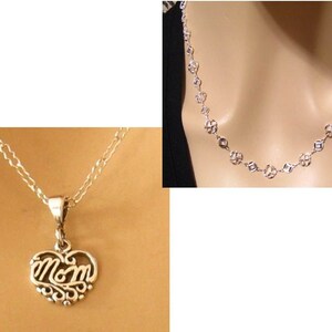 May include: Two silver necklaces. One necklace features a heart-shaped pendant with the word "Mom" in a cursive script. The other necklace is a chain with small, open circle links.