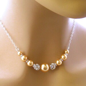 May include: A silver chain necklace with a graduated row of champagne-colored pearls and crystal accents.