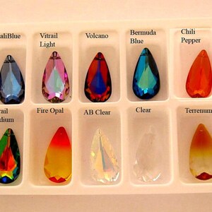 May include: A close-up view of ten teardrop-shaped crystal pendants in a white plastic tray. The pendants are arranged in two rows of five. The pendants are labeled with their names: MaliBlue, Vitrail Light, Volcano, Bermuda Blue, Chili Pepper, Vitrail Medium, Fire Opal, AB Clear, Clear, and Terrenum.