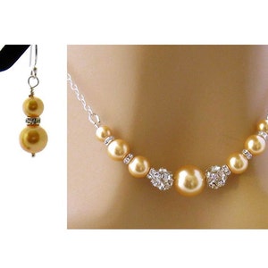 May include: A gold pearl necklace and matching earrings with crystal accents. The necklace features a row of pearls with crystal accents in between each pearl.
