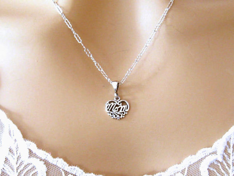 May include: A silver necklace with a heart-shaped pendant that says "Mom" in a cursive font.