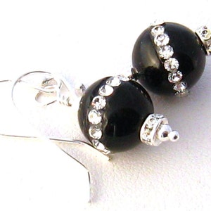 May include: Black onyx earrings with silver accents and a row of clear rhinestones around the edge of each bead.