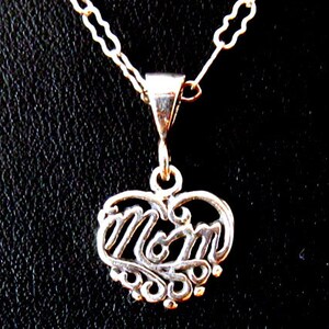 May include: Silver necklace with a heart-shaped pendant that says "Mom" in a decorative script.