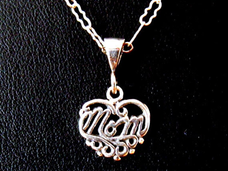 May include: Silver necklace with a heart-shaped pendant that says "Mom" in a decorative script.