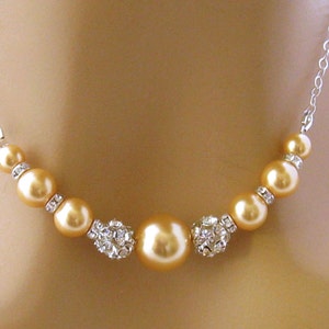 May include: A gold necklace with a silver chain and a row of gold pearls and crystal beads.