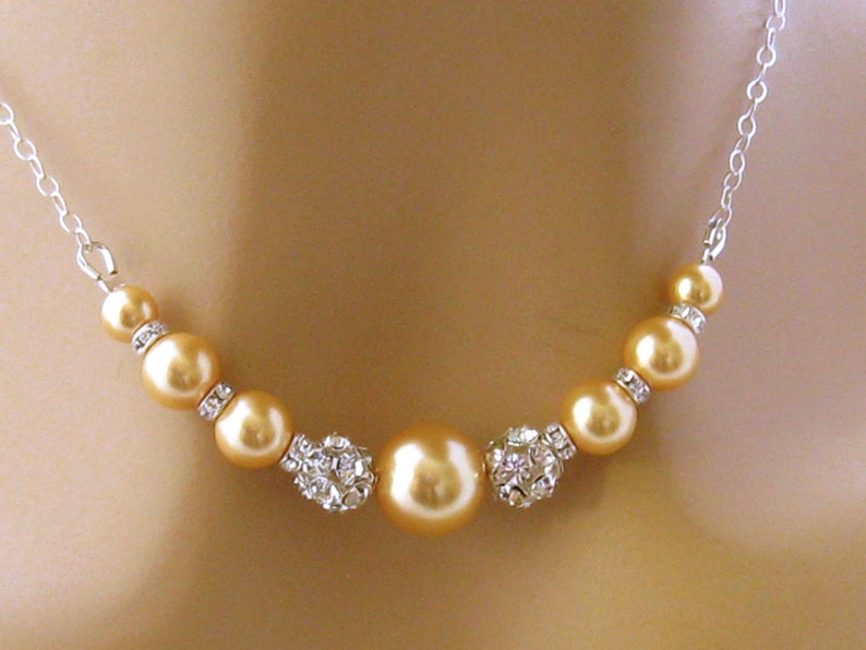 May include: A gold necklace with a silver chain and a row of gold pearls and crystal beads.