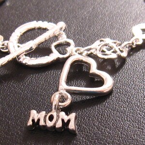 May include: Silver charm bracelet with a heart charm and a charm that says "MOM".