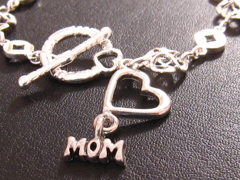 May include: Silver charm bracelet with a heart charm and a charm that says "MOM".