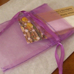 Pode incluir: Uma bolsa de organza roxa com forro de cetim branco e uma fita roxa. A bolsa cont&eacute;m um cart&atilde;o que diz "Marty's Designs Joias artesanais &uacute;nicas Marty White".