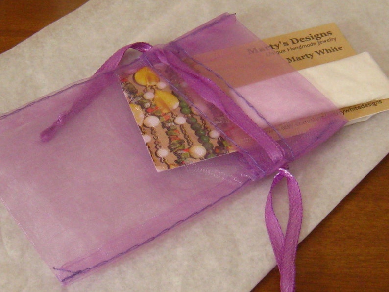 Pode incluir: Uma bolsa de organza roxa com forro de cetim branco e uma fita roxa. A bolsa cont&eacute;m um cart&atilde;o que diz "Marty's Designs Joias artesanais &uacute;nicas Marty White".