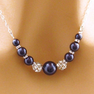 Puede incluir: Un collar de cadena de plata con una perla grande de color morado oscuro y perlas más pequeñas de color morado oscuro acentuadas con diamantes de imitación transparentes.