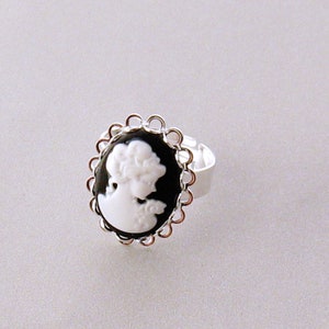 May include: A silver ring with a black cameo featuring a white silhouette of a woman's profile.
