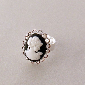 May include: A silver ring with a black cameo featuring a white silhouette of a woman's head.