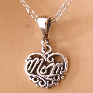 May include: A silver necklace with a heart-shaped pendant that says "MOM" in a decorative script.