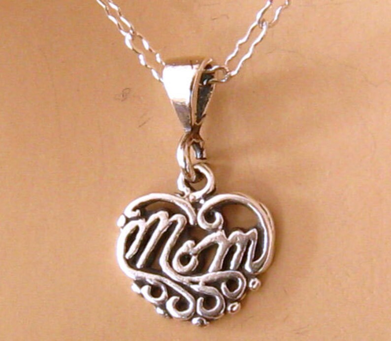 May include: A silver necklace with a heart-shaped pendant that says "MOM" in a decorative script.
