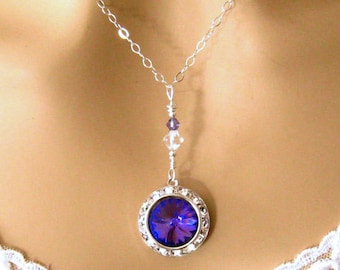 May include: A silver chain necklace with a pendant featuring a large, round, dark blue crystal surrounded by smaller clear crystals.